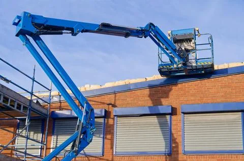 Access platform equipment powered high in sky at construction building site Stock Photos