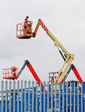 Access platform equipment powered high in sky at construction building site Stock Photos