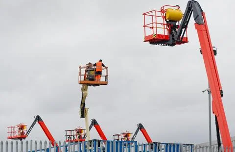 Access platform equipment powered high in sky at construction building site Stock Photos