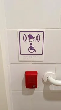 Accessible emergency alert button with braille sign on white tiled wall Stock Photos