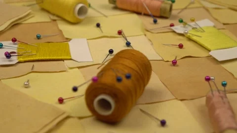 Accessories for patchwork sewing lie on a patchwork textile in yellow tones Stock Footage 260639791