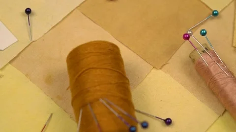 Accessories for patchwork sewing lie on a patchwork textile in yellow tones Stock Footage 260639799