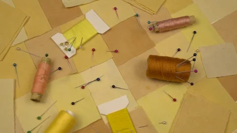 Accessories for patchwork sewing lie on a patchwork textile in yellow tones Stock Footage 260639825