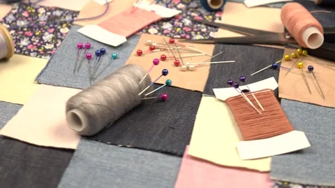 Accessories for patchwork sewing lie on a patchwork textile with printed cotton  Stock Footage 260640327