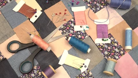 Accessories for patchwork sewing lie on a patchwork textile with printed cotton  Stock Footage 260640340