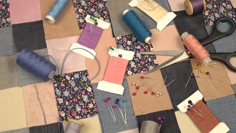 Accessories for patchwork sewing lie on a patchwork textile with printed cotton  Stock Footage 260640394