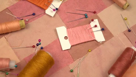 Accessories for patchwork sewing lie on a  textile in pink and brown tones Stock Footage 260639903