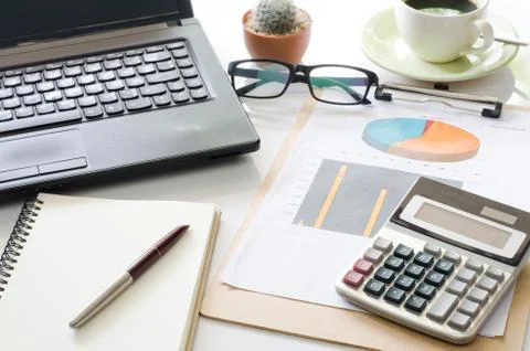 Accessories work laptop on the table, chart, calculator, pen. Stock Photos