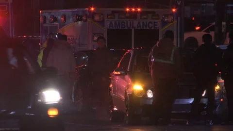 Accident at night in city intersection with ambulance and police at crash scene Stock Footage