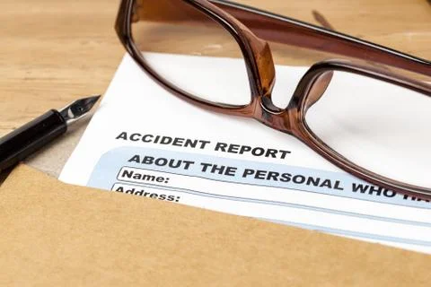 Accident report application form and pen on brown envelope and eyeglass, busi Stock Photos