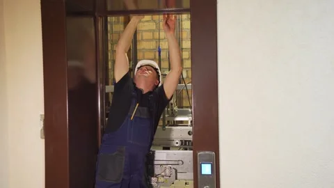 Accident, stop and repair in the elevator. A working engineer in a white helmet Stock Footage 265258259