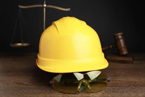 Accident at work. Hardhat, goggles, scales and gavel on wooden table, selec.. Stock Photos