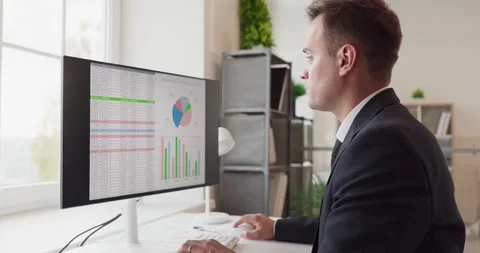 Accountant analyzing charts and spreadsheets on desktop monitor in bright office Stock Footage 331898487