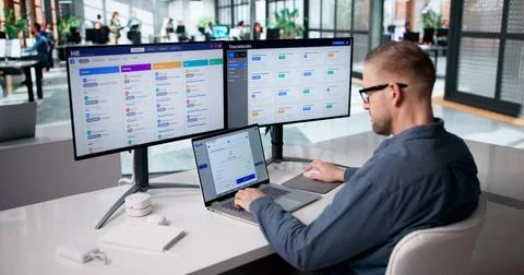 Accountant Analyzing Payroll Figures Across Several Monitors With Focus On Co Stock Photos