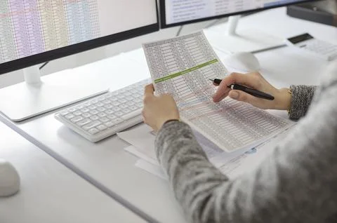 Accountant auditing financial spreadsheet data at dual monitors in office Stock Photos