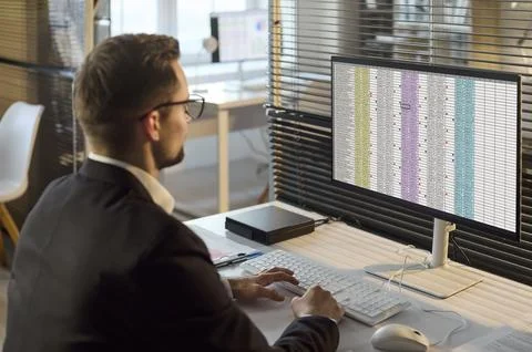 Accountant man analyzing spreadsheet data on computer monitor in modern office Foto stock