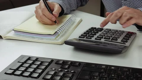 Accountant or manager making calculations and taking notes in notebook at work Stock Footage 101700132
