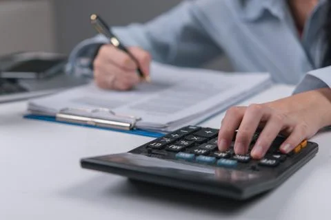 Accountant using a calculator while reviewing financial documents, highligh.. Stock Photos