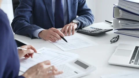 Accountants analyzing financial documents, calculating numbers together at Stock Footage 316500490