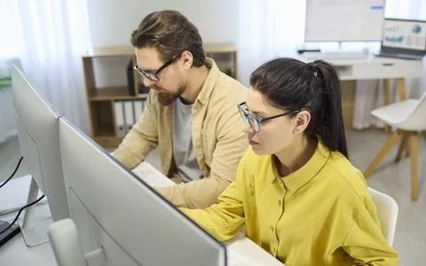 Accountants analyzing spreadsheets and reports on computers in a modern office Stock Photos
