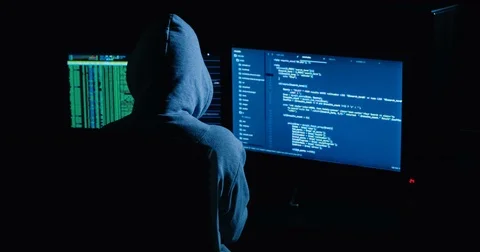 Acker in hood cracking code using laptop and computers from his dark hacker room Stock-Footage 82915981