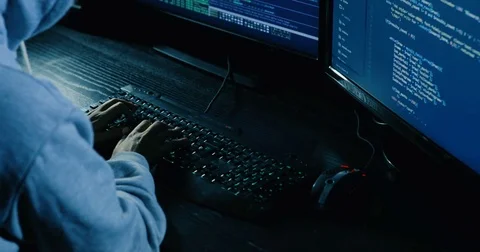 Acker in hood cracking code using laptop and computers from his dark hacker room Stock Footage 82916550