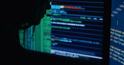 Acker in hood cracking code using laptop and computers from his dark hacker room Stock Footage 82917163