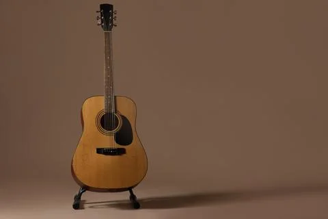 Acoustic guitar on stand with brown background Stock Photos