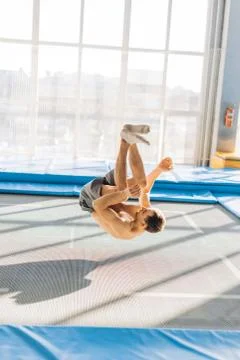 An acrobat is above a long trampoline. Stock Photos