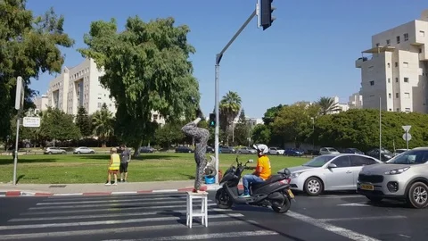 Acrobat-juggler performs hand stand on chair, middle of crosswalk, cars, Rokach Видео 80652608