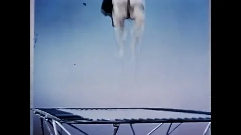 An acrobat jumps on trampoline made of mylar, a trapeze artist dangles from a Stock Footage
