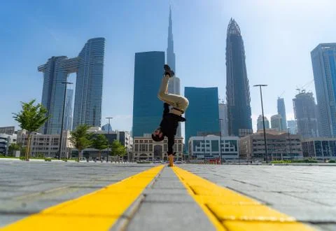 Acrobat keep balance one the hands with blurred Dubai cityscape. Concept of Stock Photos