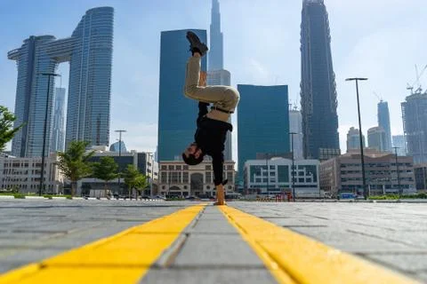 Acrobat keep balance one the hands with blurred Dubai cityscape. Concept of Stock Photos