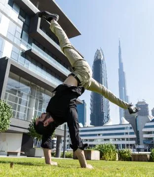 Acrobat keep balance one the hands with blurred Dubai cityscape. Concept of Stock Photos