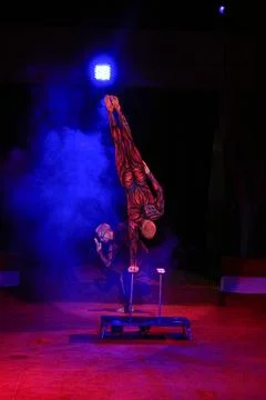 An acrobat performs a stand on one hand. blue smoke Stock Photos