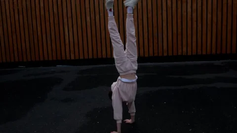 Acrobatic gymnast learning to walk on her hands and falls. A teenage girl learns Stock Footage 275879397