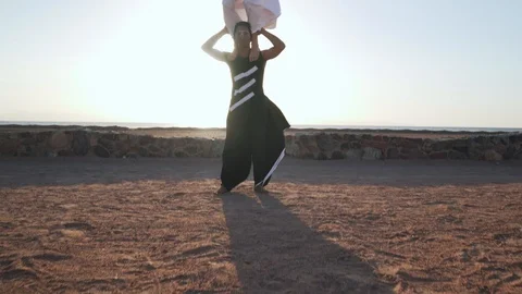 Acrobatic shoulder stand performance in windy desert in sun glare shaky footage Stock Footage 99499539