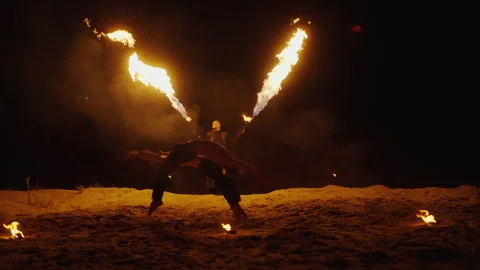 Acrobats Jumping On Sand In Night, Firemaster Illuminating Space By Burning Stock Footage 254318486