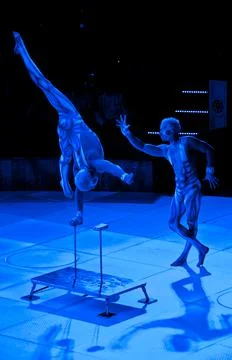 Acrobats perform one-arm handstand, neon costumes Stock Photos