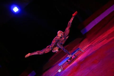 Acrobats in red suits perform a trick on their hands. Stock Photos