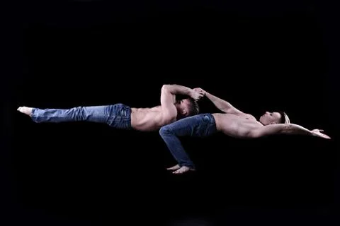 Acrobats twins perform a gymnastic element. naked torso, blue jeans. Stock Photos