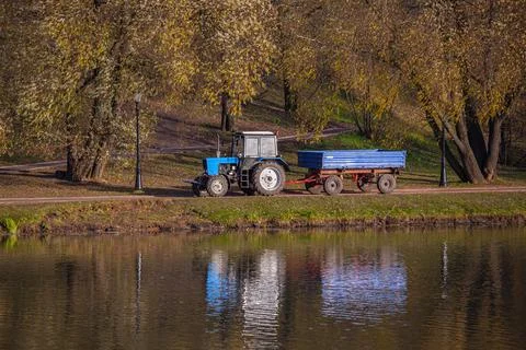 Across the fields, a blue tractor is coming to us, near the water with a Stock Photos