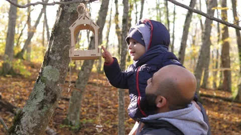 Act of kindness. Cute 2 years old boy sits on dad shoulders and puts food in Stock Footage 220850565