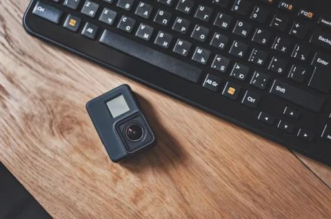 Action-Camera on the background of a black keyboard on a wooden table. Stock Photos
