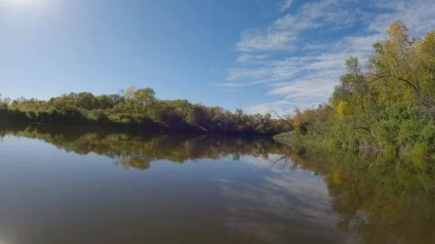 Action camera on a canoe moving along a calm river with blue sky and fall colors Stock Footage 287107444