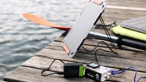 An action camera is charged from a small solar panel at the wooden pier. Stock Footage 157789244