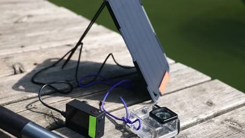 An action camera is charged from a small solar panel at the wooden pier. Stock Footage 157789438