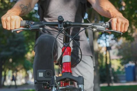 Action camera fixed next to the wheel of the bicycle on which the man rides Stock Photos