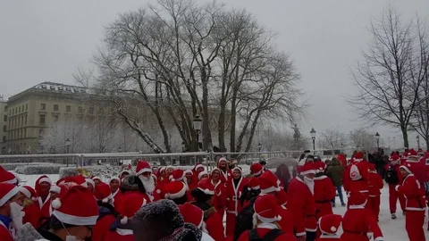 Action camera moves smoothly behind crowd of Santa Clauses running in heavy snow Stock Footage 70633309