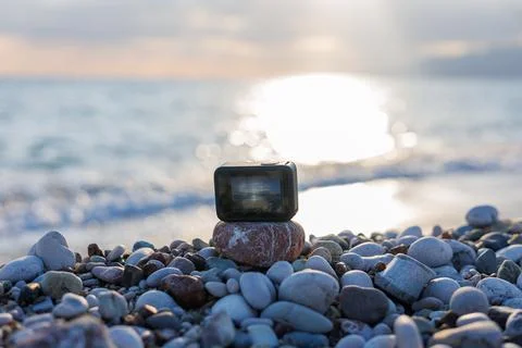 Action camera on pebbled beach at sunset Stock Photos